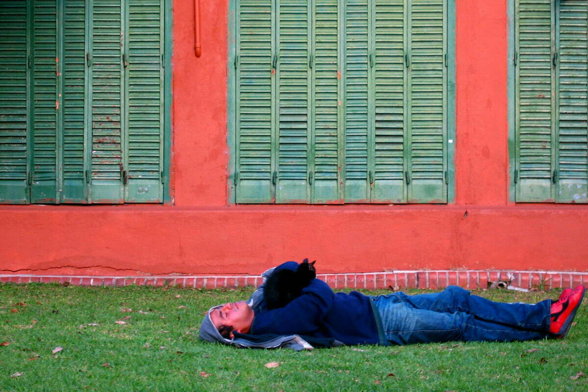 A man sleeps with a cat on his chest near a shuttered building at the famously cat-ridden Buenos Aires Botanical Garden in the Palermo neighborhood of Buenos Aires, Argentina.