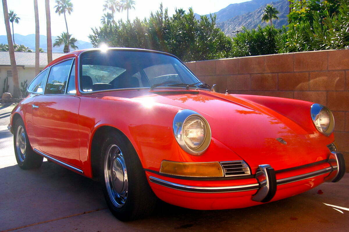 An orange classic 911 Porsche sits in a driveway of a home in Palm Springs, California.