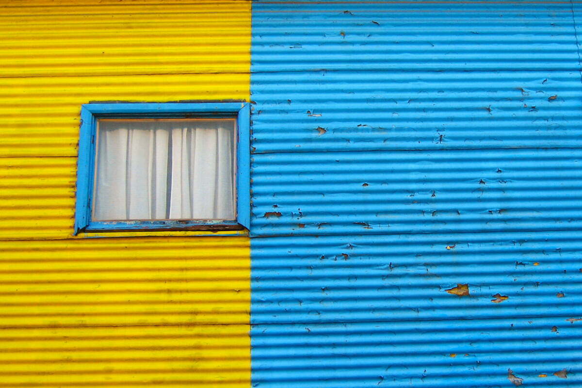 The wall of a house with bright blue and yellow paint in the La Boca neighborhood of Buenos Aires, Argentina.
