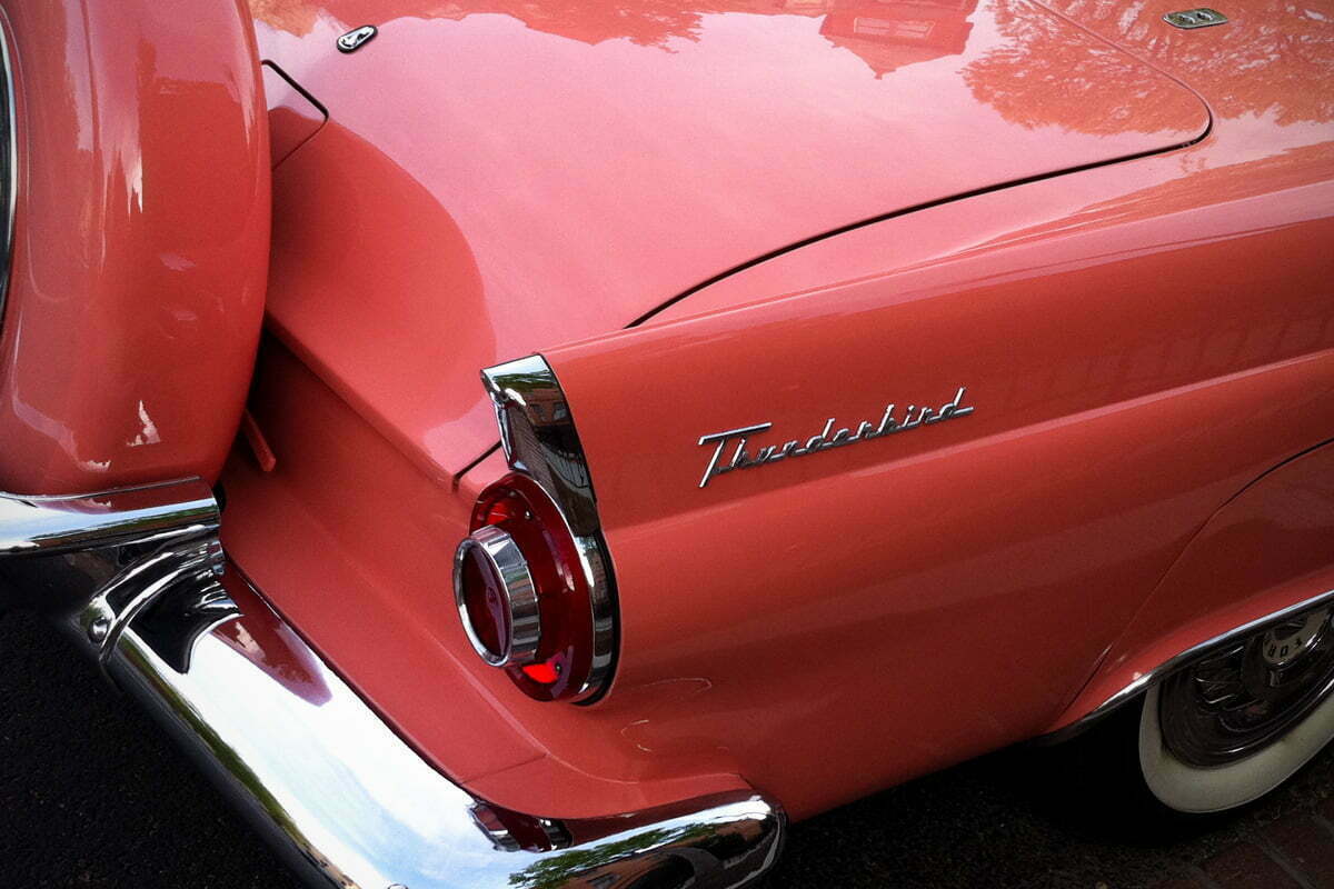 The rear of a classic pink Ford Thunderbird from the 50s or 60s.