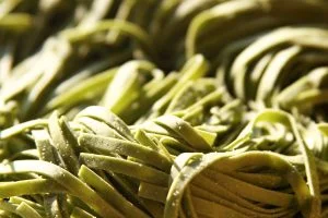 A closeup of a pile of freshly made green pasta.