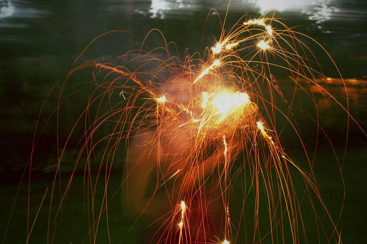 A girl sets off fireworks and a sparkler before Independence Day.