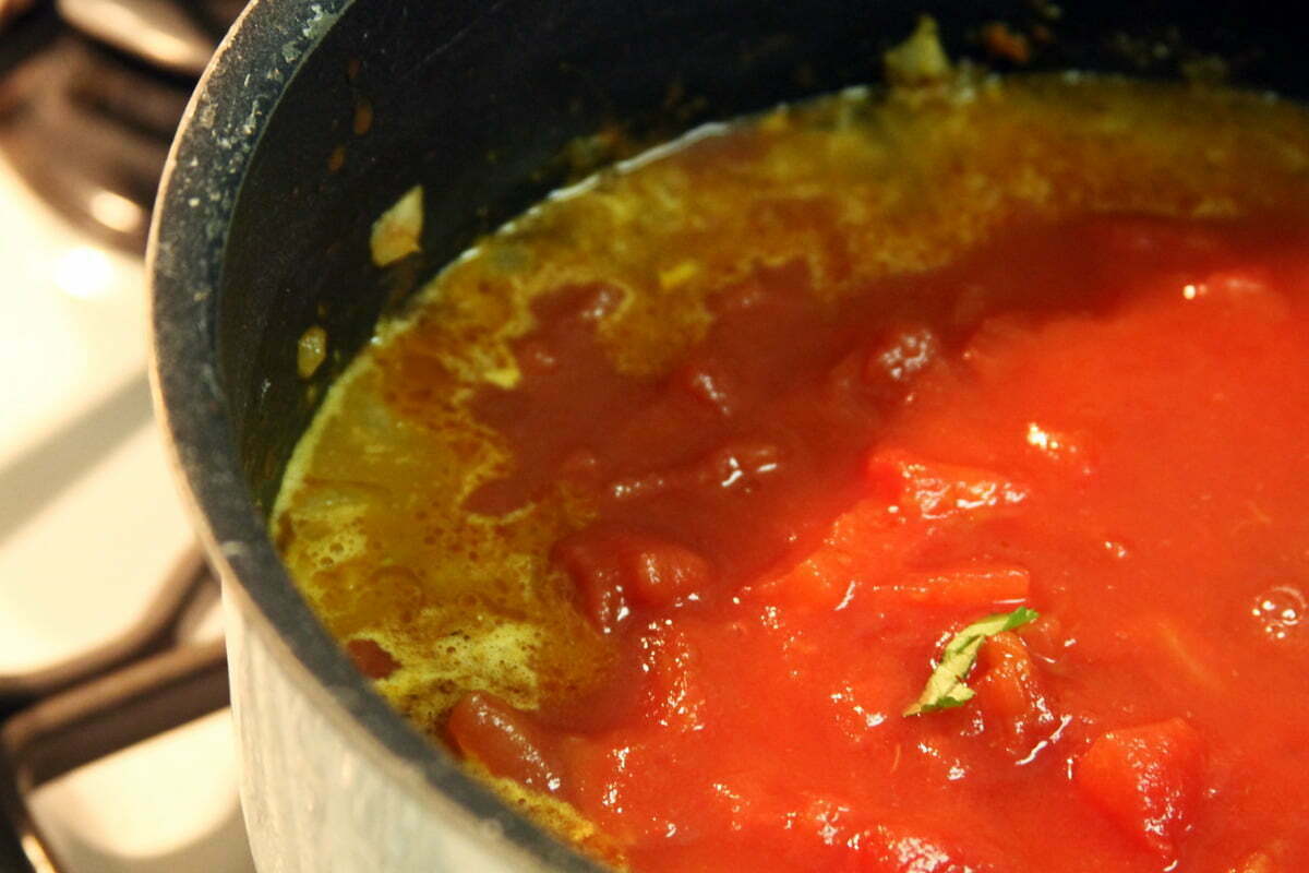 The reddish mixture of spices and tomatos sit on the stovetop to make a spicy Moroccan stew.