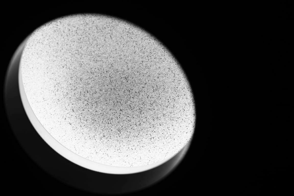 A surreal black and white image of a speckled countertop through a light ring.