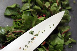 A knife lies onto of a bed of rhubarb chard after a thorough slicing.