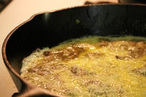 A frittata starting to cook in a hot cast iron skillet.
