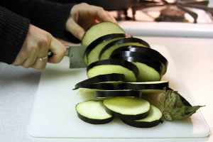 An eggplant is sliced on the cutting board.