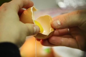 Sally cracks an egg and demonstrates the process of separating the white from the yolk.