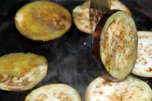 A fork turns some steaming pieces of eggplant.