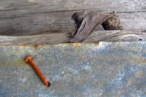 A red rusty nail sticks out of some aluminum sheet metal and wood in Valparaiso, Chile.