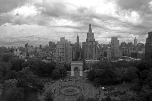 A black and white skyline view of New York City over Washington Square Park on an overcast day.