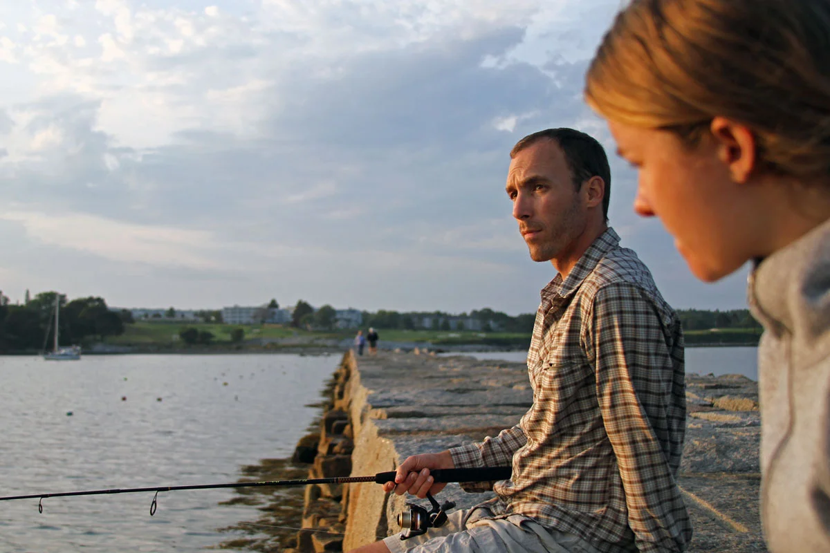 A man and woman fish on the breakwater in Rockland, Maine.