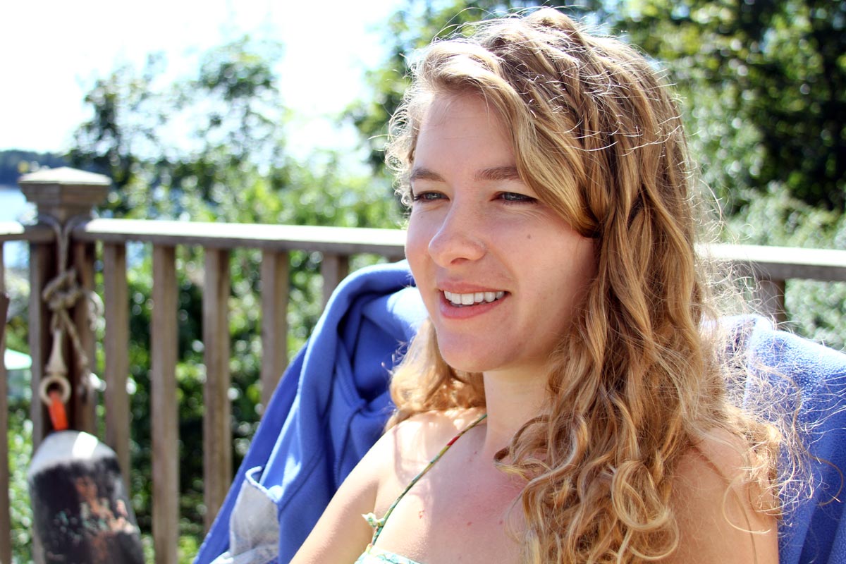 A woman with curly blond hair sits in the Maine sunshine.