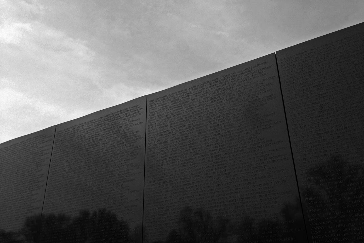 A black and white photo of the wall of names of lost soldiers from the Vietnam War in Washington DC.