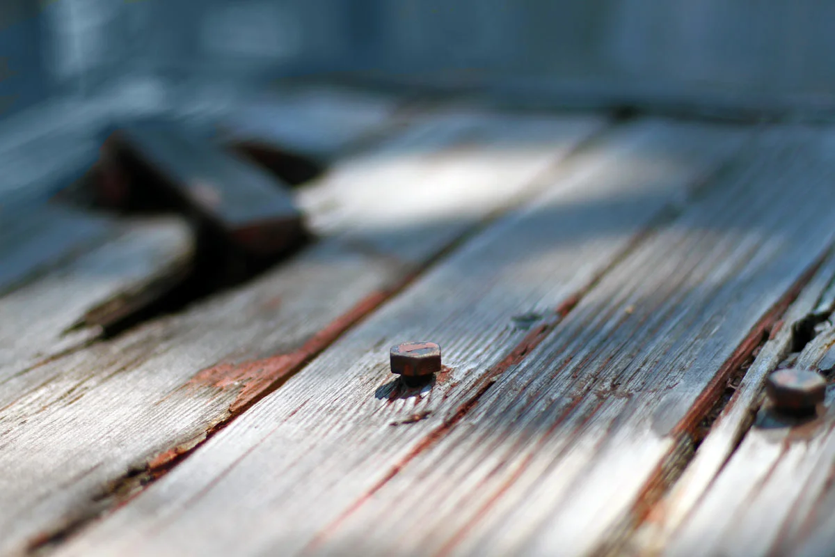 A hex screw in a weather worn, old wood table.