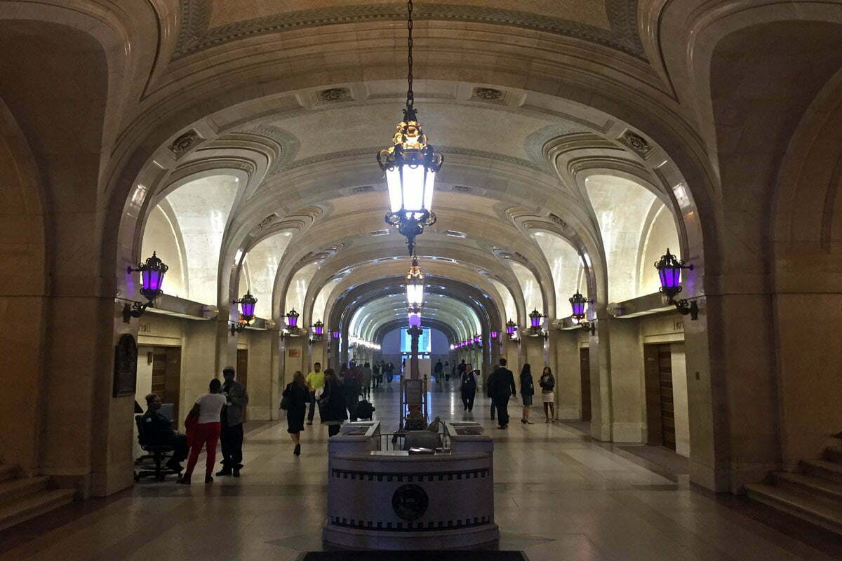 The ornate hallways of the lobby in the Chicago City Hall building with purple lights.