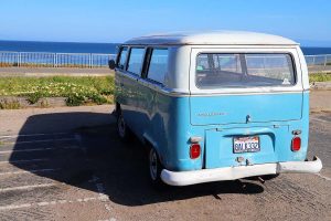 A blue Volkswagen bus parked on the cliffs of Santa Cruz, California overlooking the Pacific Ocean.