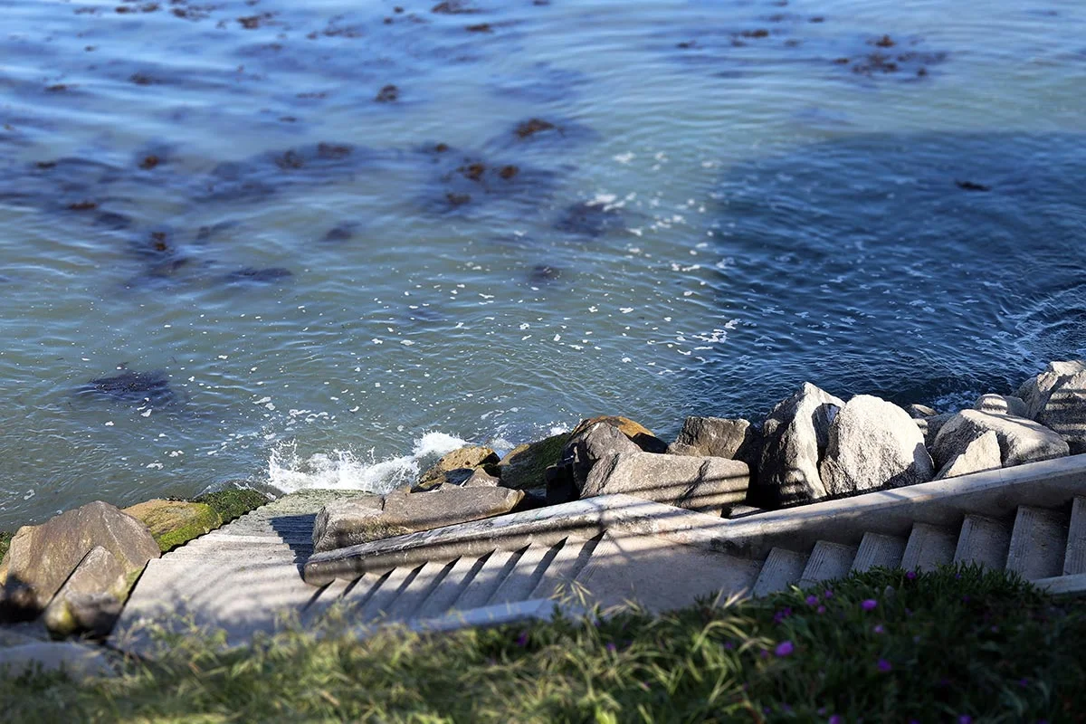 Waves crash into the stone steps used by surfers that goes down to the ocean in Santa Cruz, California.