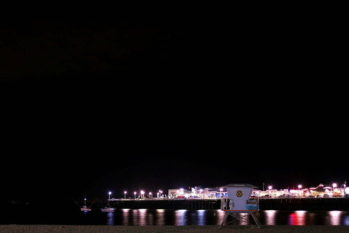 The Santa Cruz Wharf seen in the dark from the beach on a summer night in California.