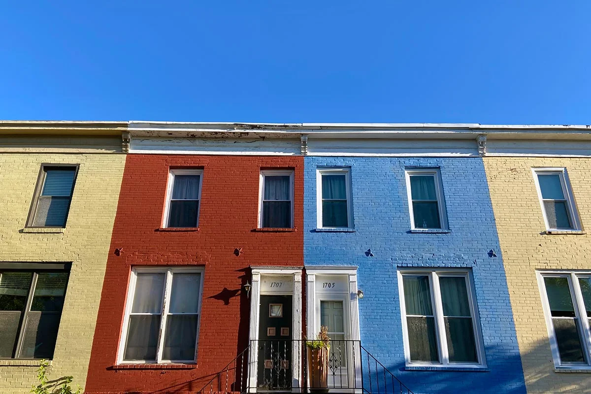 The front of a series of attached row houses in different colors seen on Seaton Street NW in Washington DC.